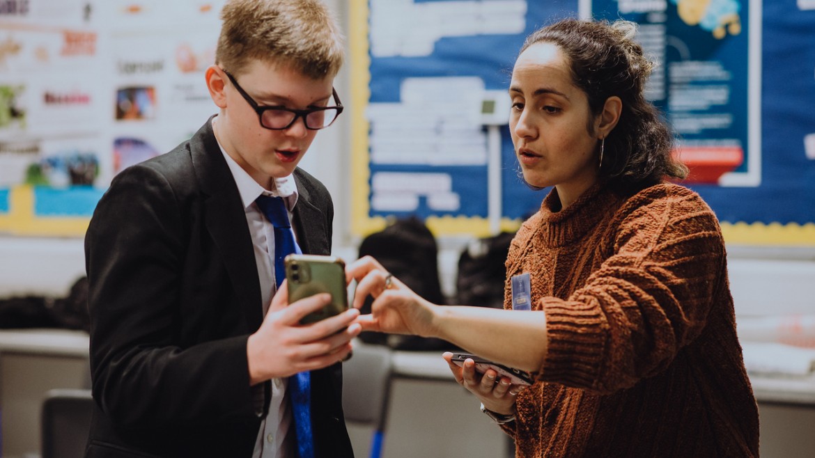 Teacher supporting student with mobile phone filmmaking